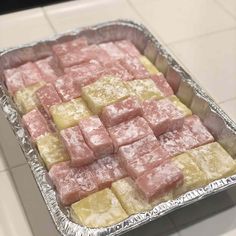 a pan filled with pink and yellow squares of food on top of a countertop