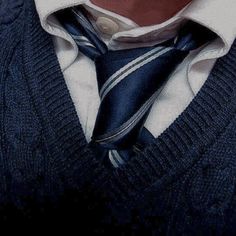 a man in a sweater and tie is wearing a white shirt with blue stripes on it