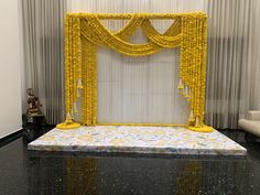 a stage set up for a wedding with yellow flowers on the floor and curtains behind it