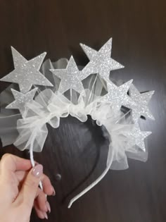 a hand is holding a white headband with silver stars and tulle on it