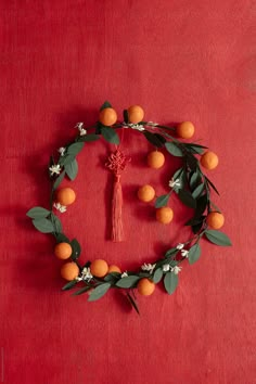 oranges arranged in a circle with leaves and flowers on a red tablecloth background