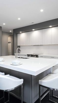 a large kitchen with white counter tops and chairs