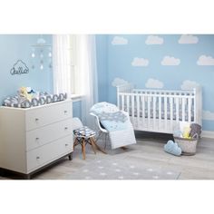 a baby's room with blue walls and clouds painted on the wall behind it