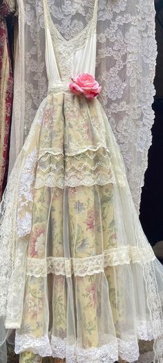 a white dress with pink flower on the back and lace overlays, hanging from a rack