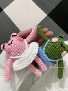 crocheted peppa pig and frog amigurt dolls are being held by someone's hand