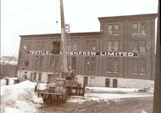 an old black and white photo of a crane in front of a building