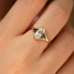 a woman's hand with a yellow gold ring on top of it and a diamond in the middle