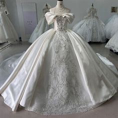 a white wedding dress on display in a shop window with other dresses and gowns behind it