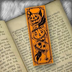 an orange bookmark with pumpkins on it sitting next to an open book,