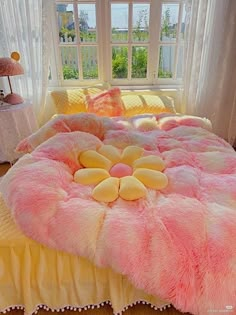 a pink and yellow bed with flowers on the comforter in front of a window