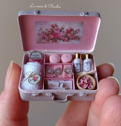 someone is holding a miniature pink box with items inside