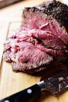 a piece of meat sitting on top of a cutting board next to a knife