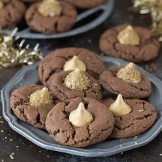 chocolate cookies with peanut butter frosting and gold sprinkles on a plate