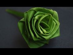 a green rose is sitting on a black surface and it looks like it has been folded