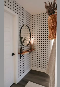 a bathroom with black and white wallpaper has a round mirror on the wall next to it