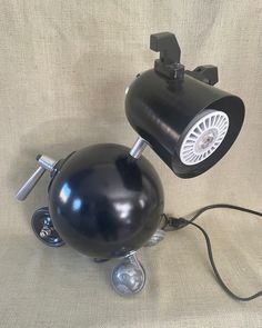 a black desk lamp sitting on top of a white cloth covered floor next to a light bulb