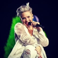 a woman sitting on top of a chair while holding a microphone in her right hand