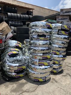 several tires stacked on top of each other in front of a truck with another tire behind them