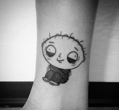 a small black and white tattoo of a little boy with big eyes on his leg