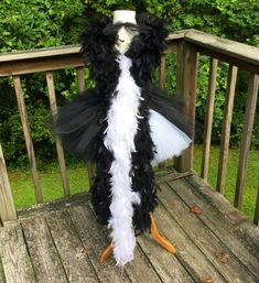 a black and white feathered costume on a wooden deck