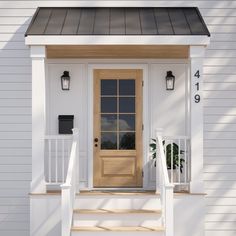 a white house with a wooden door and steps leading up to the front porch area