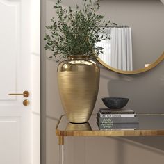 a gold vase sitting on top of a wooden table next to a mirror and books