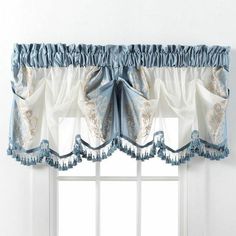 a window with a blue and white valance hanging from it's side next to a potted plant