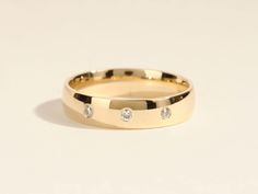 a yellow gold wedding ring with three diamonds on the inside, set against a plain white background