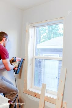 a man in red shirt working on a window sill next to a white wall