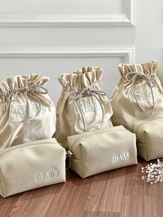 three personalized bags sitting on top of a wooden floor next to a bag filled with pearls