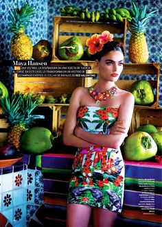 a woman standing in front of a display of fruit and pineapples with her arms crossed