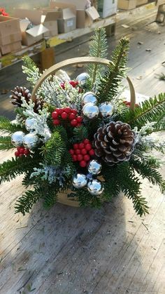 a basket filled with pine cones, berries and greenery on top of a wooden table