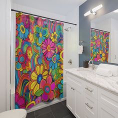 a colorful shower curtain in a bathroom next to a white toilet and sink with a mirror on the wall