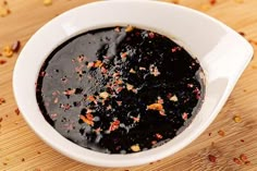 a white bowl filled with black sauce on top of a wooden table