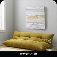 a yellow futon bed sitting in front of a window