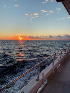 the sun is setting over the ocean on a boat