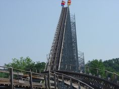 a roller coaster with flags flying from it's top