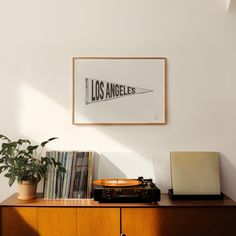 a record player sitting on top of a wooden cabinet next to a plant and records