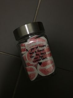 a jar filled with pink and white candies sitting on top of a tiled floor