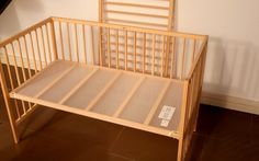 a small wooden crib sitting on top of a hard wood floor next to a wall