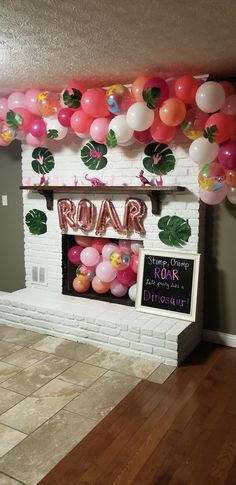 a decorated fireplace with balloons and a chalkboard sign in front of it that says roar