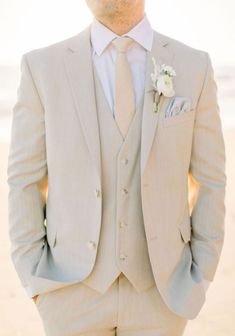 a man in a suit and tie standing on the beach