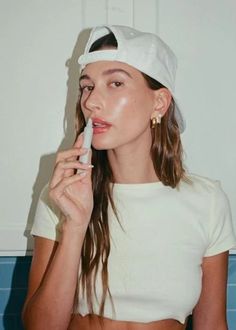 a woman brushing her teeth with a white hat on top of her head and blue tiles behind her