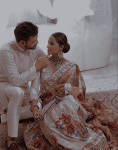 a man and woman sitting next to each other on a bed in their wedding outfits