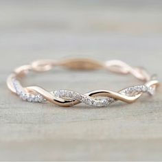 a rose gold wedding band with white diamonds in the shape of an intertwined ring