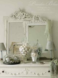 a white dresser topped with vases filled with flowers and eggs next to a mirror