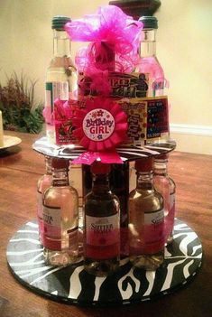 there is a cake made out of liquor bottles on a plate with pink ribbon around the top