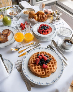 a white table topped with waffles and fruit