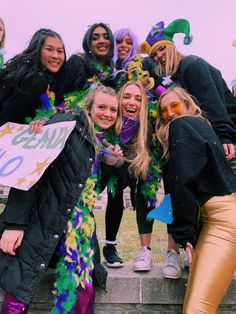 a group of women standing next to each other in front of a crowd wearing mardi gras costumes