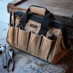 a tool bag sitting on top of a table next to a pair of wrenches